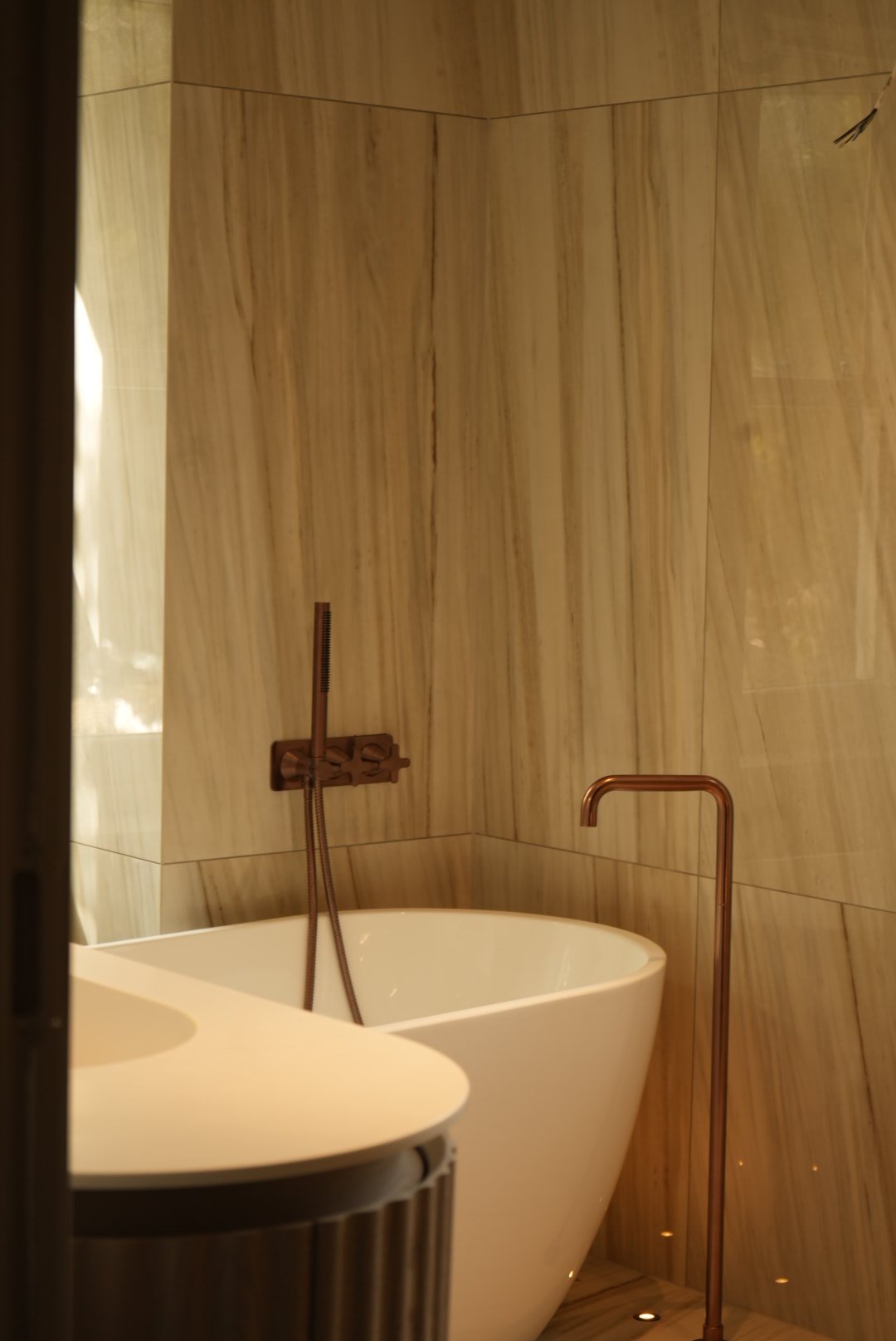 A freestanding bath against veined stone walls