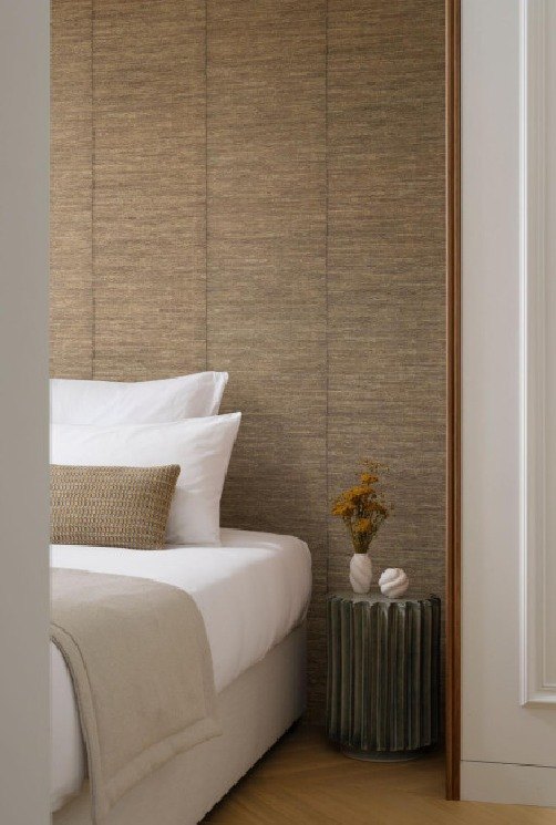 A grasscloth headboard wall framed in oak