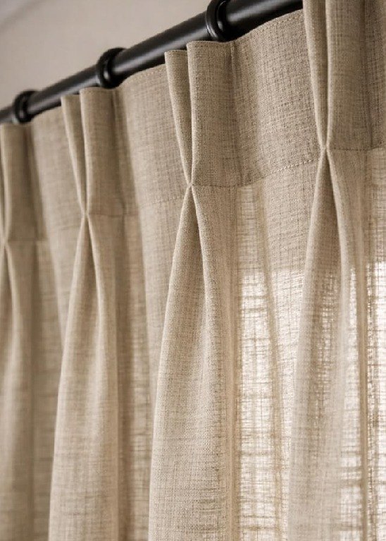 Pinch-pleat linen drapery on a slim bronze rod