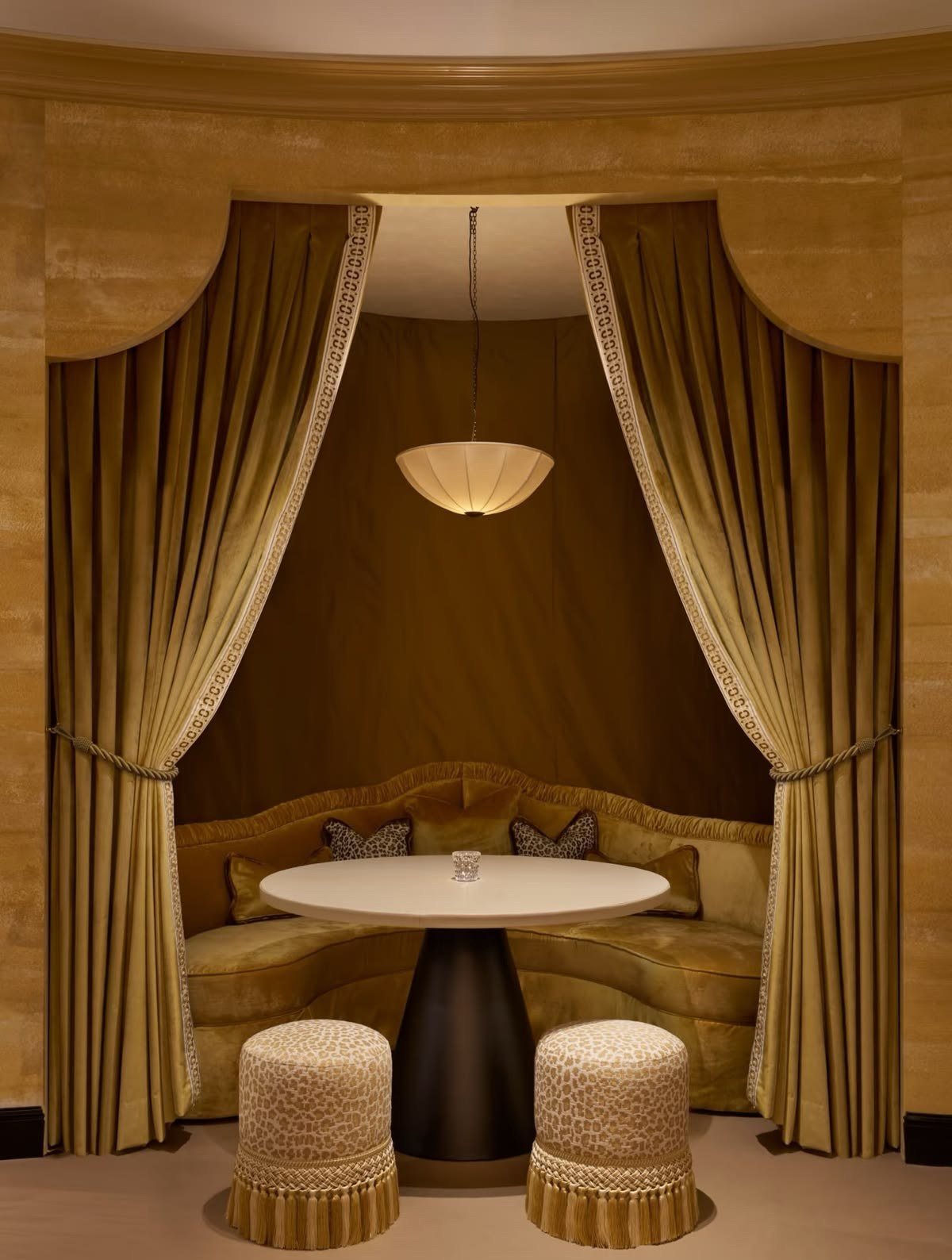 A velvet curtained banquette beneath a silk pendant