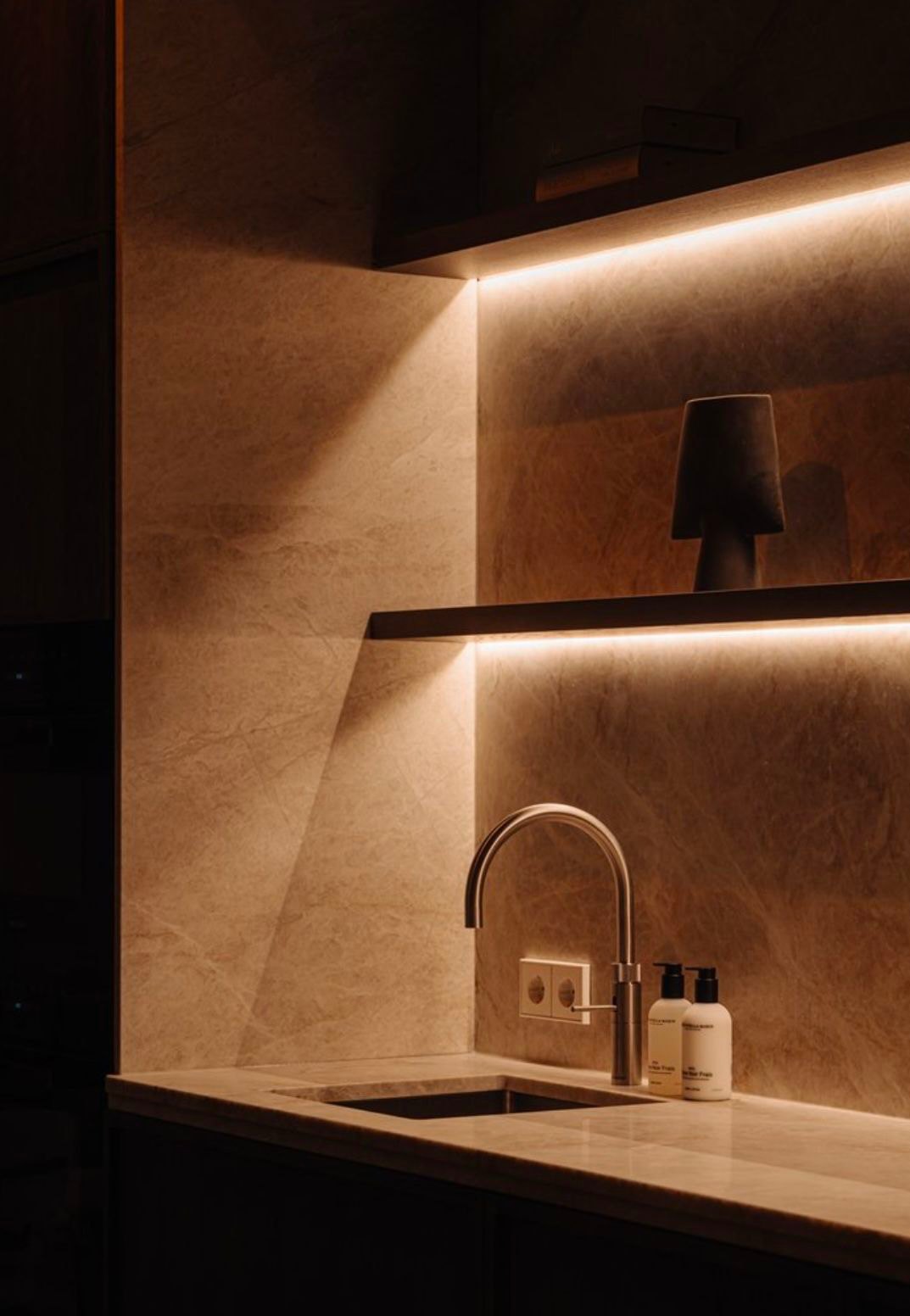 Concealed warm lighting along a stone wall and shelf